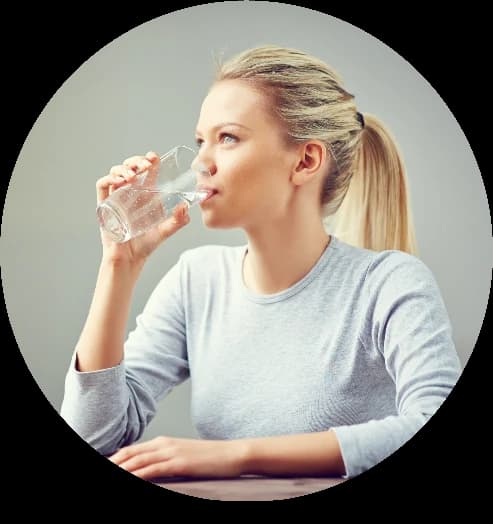 A person drinking a glass of clear water, illustrating the smooth, soft taste of dynamized water